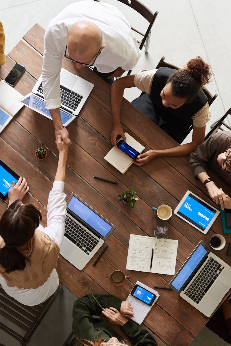 Top view of a diverse team collaborating in an office setting with laptops and tablets, promoting cooperation.